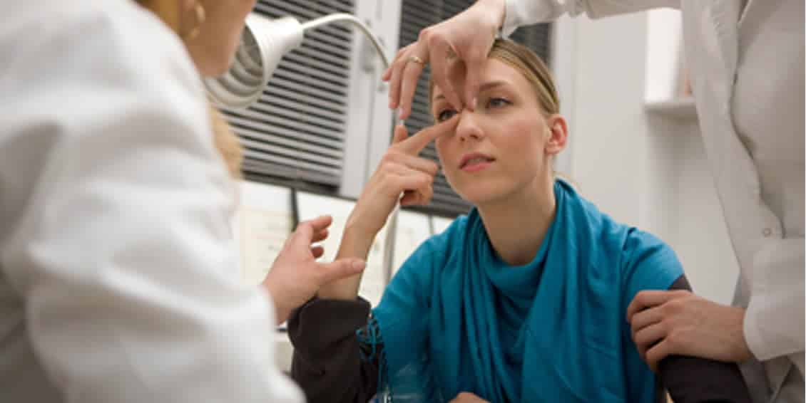 Woman being examined by to doctors prior to a rhinoplasty procedure, in Doctor's office